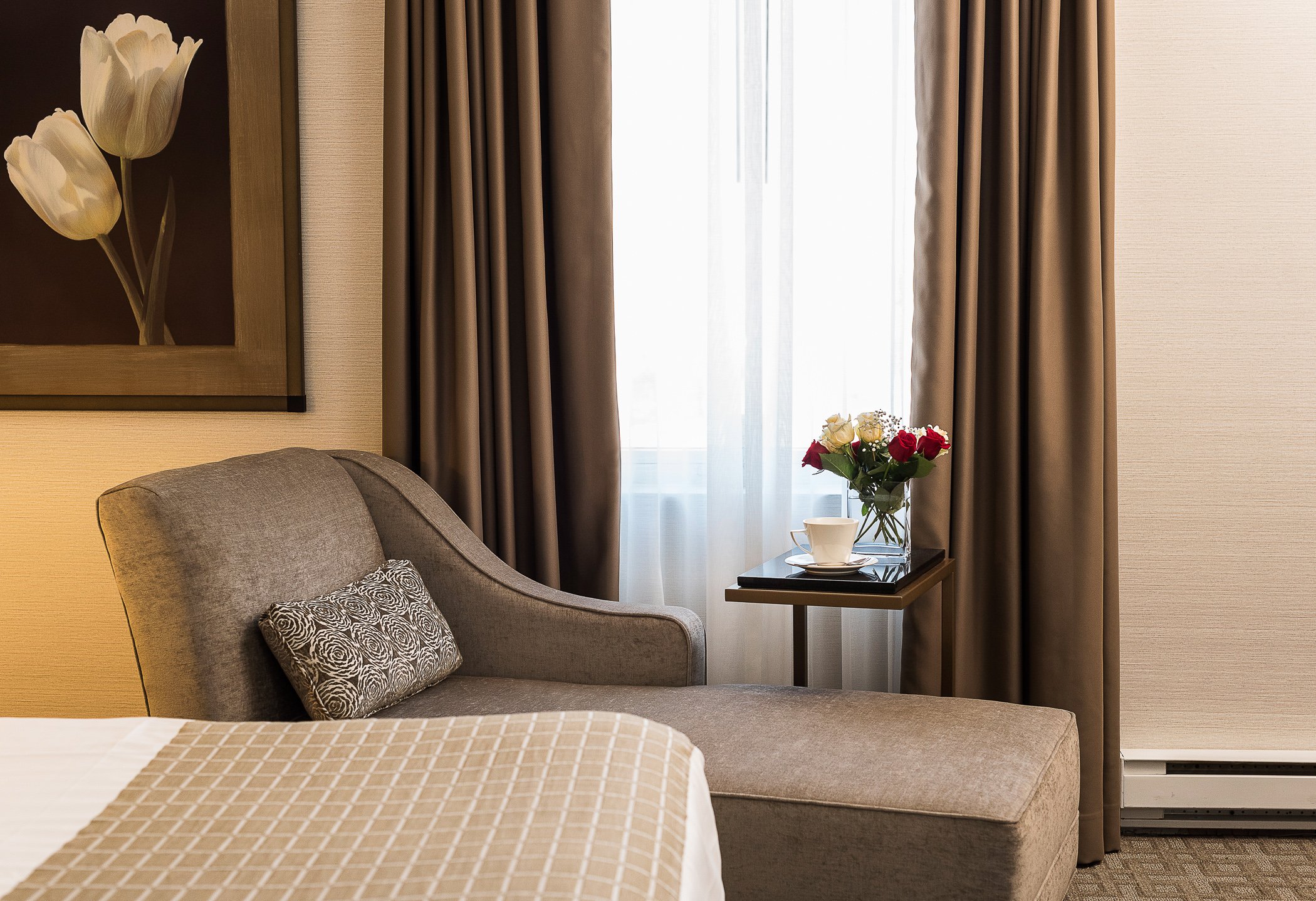 An armchair and a bouquet of flowers inside a room at the Lord Elgin Hotel.