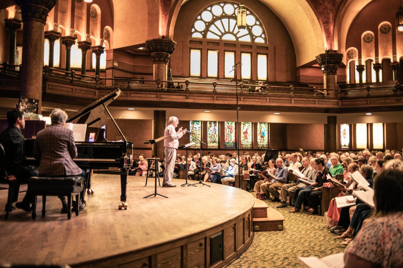 A man stands on stage speaking to a crowd of people in a church.