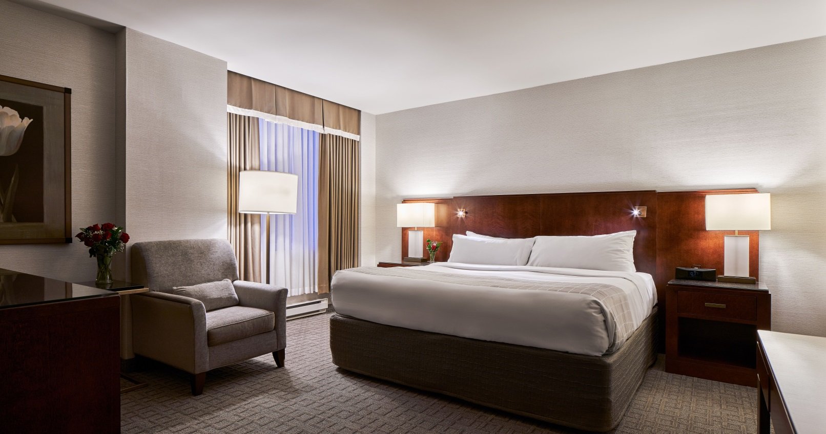 A Lord Elgin Hotel room featuring a queen bed, a chair and floor to ceiling windows.