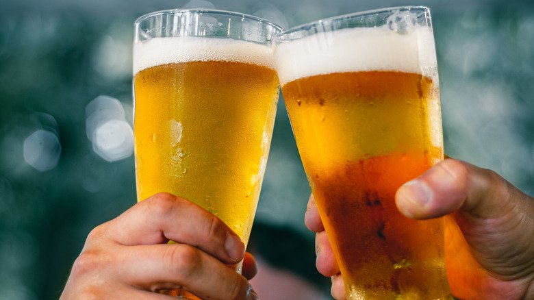 Two people tapping their beer glasses together in cheers.